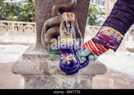 Hand eine Schale füllen mit therapeutischen Mineralwasser bei einer natürlichen heißen Quelle in Karlsbad im Winter, Tschechische Republik Stockfoto