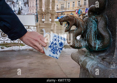 Hand eine Schale füllen mit therapeutischen Mineralwasser bei einer natürlichen heißen Quelle in Karlsbad im Winter, Tschechische Republik Stockfoto