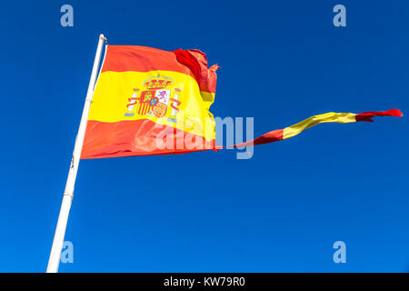 Close-up zerrissen spanische Flagge schwenkten auf dem Wind auf dem Mast über dem klaren, blauen Himmel Hintergrund Stockfoto