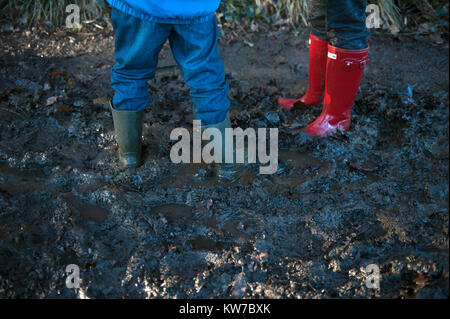 Zwei Kinder tragen Gummistiefel im Schlamm Stockfoto