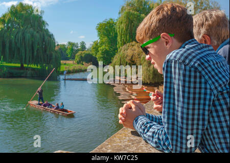 Cambridge UK-Punt, an einem Sommernachmittag beobachtet ein junger Tourist auf der Silver Street Bridge Leute, die auf dem River Cam, Cambridge, England, poken. Stockfoto