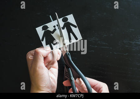 Familie Scheidung. Zugeschnittenes Bild von Hand schneiden von Papier Familie mit der Schere über Holz- Tabelle. Stockfoto