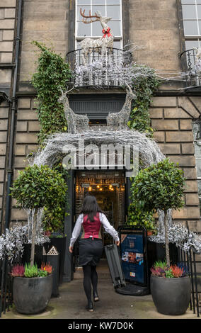 Mitarbeiter, der das georgianische Stadthaus vor der Scotch Malt Whisky Society, Queen Street, Edinburgh, Schottland, Großbritannien, mit Weihnachtsdekorationen betritt Stockfoto