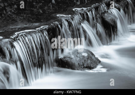 Der Fluss Dove über eine kleine Wehr in den einsamen Wäldern Tal von Beresford Dale im Peak District National Park, England, Großbritannien Stockfoto