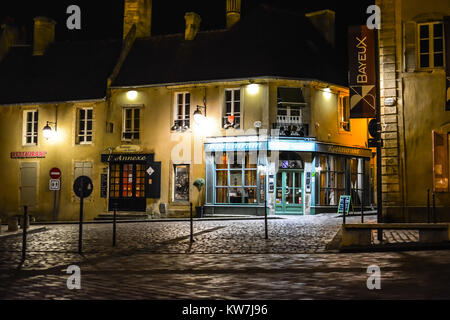 Ein Restaurant beleuchtet unter den Lichtern in der Nacht auf einer leeren Straße in der mittelalterlichen Stadt Bayeux an der Küste der Normandie in Frankreich Stockfoto