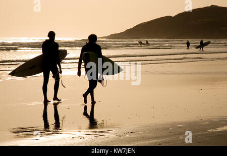 Paar Spaziergang am Strand in Großbritannien zusammen Holding Surfbretter Stockfoto