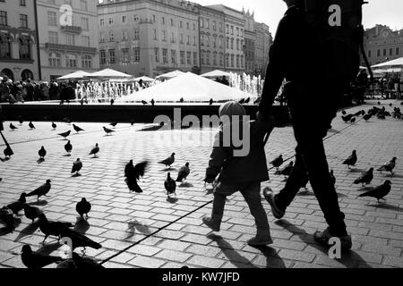 Kind mit Eltern Hand zu Fuß durch Krakau Square Stockfoto