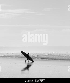 Surfer Spaziergänge an einem Sandstrand mit einem Surfbrett Stockfoto