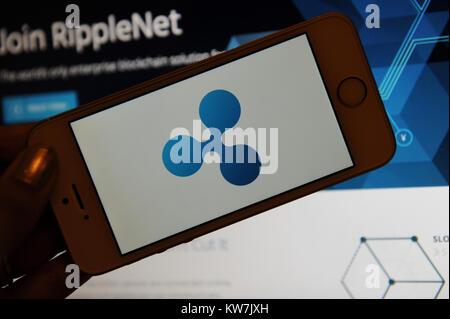 Die Welligkeit Logo ist auf einem Telefonbildschirm und RippleNet auf einem Computer gesehen Stockfoto