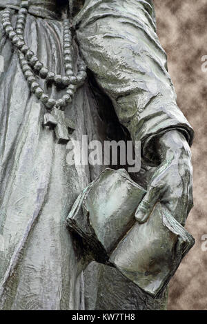 Bronzestatue von einem Missionar, trägt einen Rosenkranz und hält eine Bibel in der Hand Stockfoto