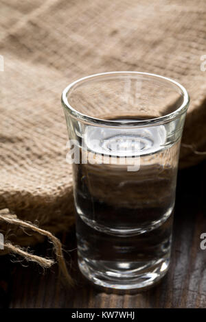 Deutschen Schnaps Korn Schnaps in shot Glas mit sackleinen Sack auf rustikalen Holztisch Stockfoto