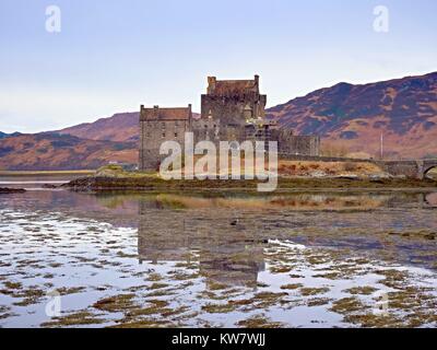 Gezeiten der See am Eilean Donan Castle, Schottland. Die beliebten steinerne Brücke über die Reste von Wasser mit massiven Büschel von Wasser Algen. Schwaches Licht Stockfoto