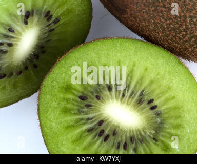 Grüne Kiwi in der Hälfte neben ganzen auf weißem Hintergrund Stockfoto
