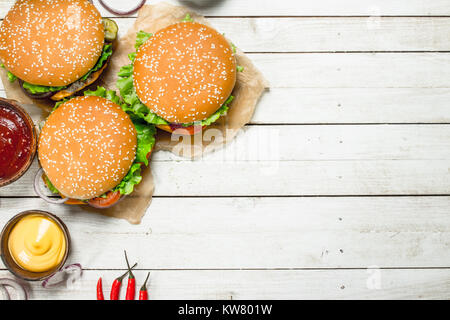 Burger mit frischem Rindfleisch, Käse und Gemüse. Auf einem weißen Holz- Hintergrund. Stockfoto