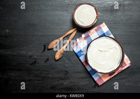 Natürliche Milch Joghurt in eine Schüssel geben und mit einem Löffel. Auf der schwarzen Tafel. Stockfoto