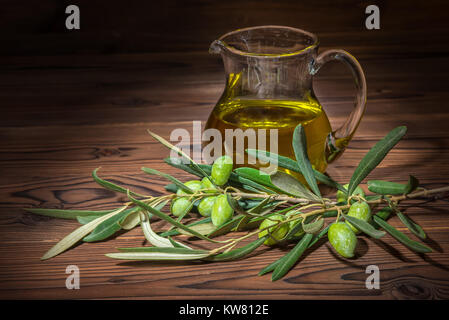 Grüne Zweige der Olivenbaum mit Beeren und frisches Öl auf Holz- Hintergrund, rustikalen Stil Stockfoto