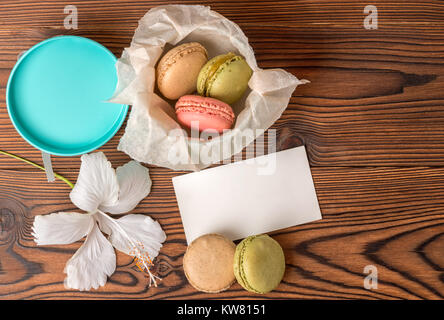 Blick von oben auf die bunte macarons Kuchen in Geschenkbox, leer, leer, und Hibiscus flower auf Holz- Hintergrund, kopieren Raum Stockfoto