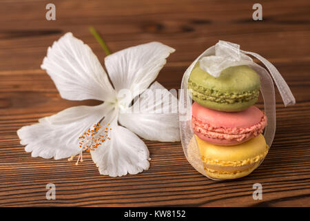 Bunte macarons Kuchen Band und Hibiscus flower auf Holz- Hintergrund gebunden, urlaub Konzept Stockfoto