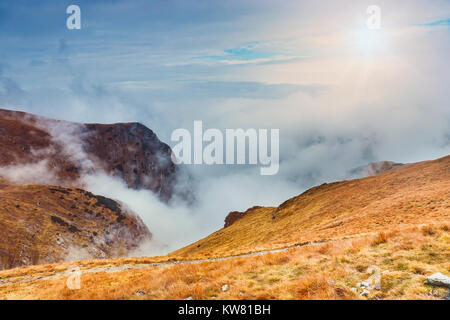 Berglandschaft mit Nebel unter dem Gipfel und Wolken über Ihnen in blauen Farbtönen Stockfoto