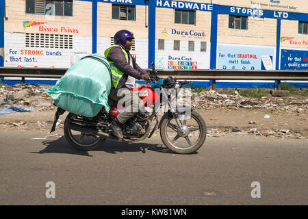 Ein männlicher Boda boda Motorradfahrer tragen eine große Tasche auf der Rückseite seines Motorrades, Nairobi, Kenia, Ostafrika Stockfoto