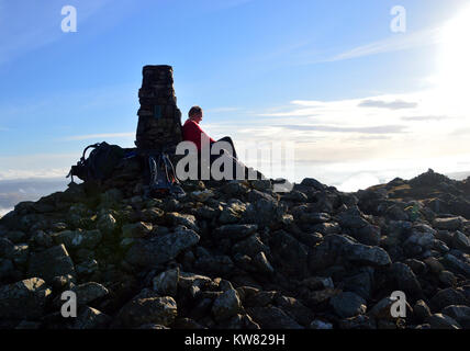 Einsame männliche Hillwaker Ruhen Seine Augen und den Sonnenuntergang auf dem Gipfel des Welsh Mountain Aran Fawddwy in der Snowdownia National Park, Wales. Stockfoto