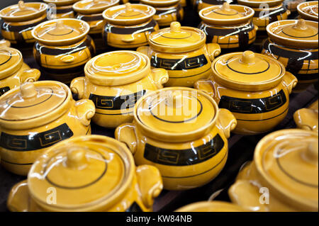 Keramik Becher und Schalen mit gelb-braune Farbe im Store auf dem Zähler stehen in einem Haufen. Verkauf, Handel. Stockfoto