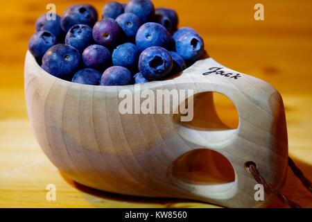 Heidelbeeren im Finnischen Holz- kuksy Schale auf einem hölzernen Schreibtisch. Nordeuropäischen noch Leben und sauber Essen Superfood. Winter 2017. Stockfoto