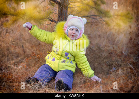 Süße kleine Mädchen sitzt auf dem Boden im Herbst Park Stockfoto