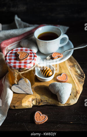 Tasse Tee mit Zitrone und Honig und herzförmige Plätzchen auf rustikalen Hintergrund Stockfoto