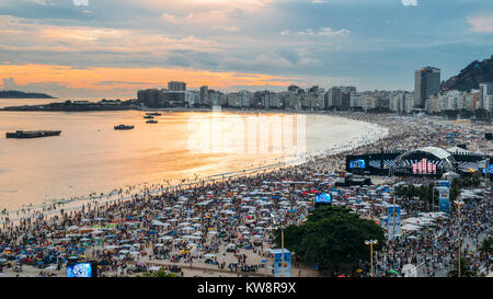 Rio de Janeiro, Brasilien - Dec 31, 2017: Luftaufnahme von Copacabana Strand bei Sonnenuntergang als Partygänger warten für die ikonischen Feuerwerk. Eine Bühne ist bis auf den Strand gesetzt und wird live Performances Stockfoto