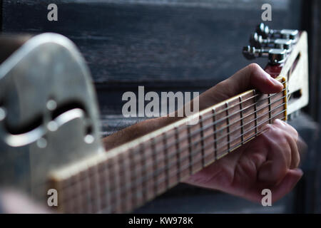 Finger spielen akustische Gitarre auf schwarzem Hintergrund aus dunklem Holz mit selektiven Fokus und Bewegungsunschärfe Stockfoto