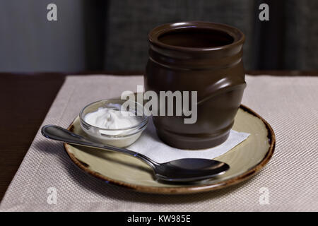 Soljanka - russische traditionelle Fleischsuppe. Russische Suppe Mönchsbart in Runde Platte auf hölzernen Hintergrund. Stockfoto