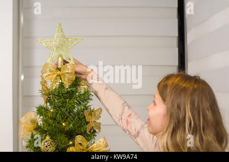 Tolles Konzept von Weihnachten Frau putting Stern am Weihnachtsbaum. Stockfoto