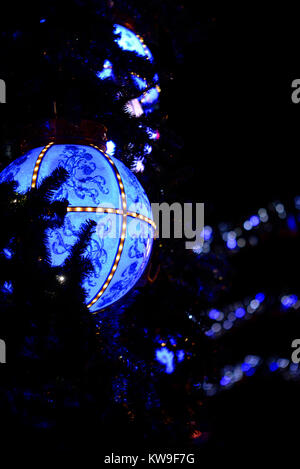 Große blaue Weihnachtskugel, beleuchtet bei Nacht. Vintage-Blumendesign. Auf einem Weihnachtsbaum draußen Stockfoto
