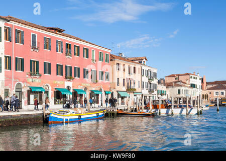 Trattoria Antica auf Riva Longa, Murano, Venedig, Italien, mit Menschen zu Fuß und Einkaufs- und bunte Boote im Vordergrund. Stockfoto