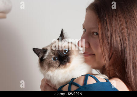 Junge Frau umarmte ihre Seal Point Birma Katze, 9 Monate alten Katze, Mann mit blauen Augen Stockfoto