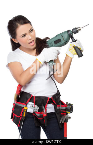 Frauen tragen Arbeitskleidung mit toolbelt mit elektrischen Bohrmaschine Stockfoto