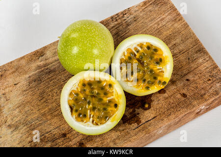 Eine Gruppe von Passionsfrucht in einem Holz, zwei Hälften einer maracuja Frucht, die mit dem Teig und die Samen in Sicht Stockfoto