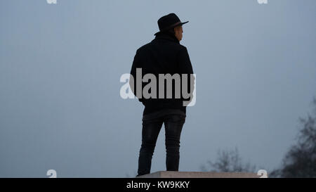 Mann in Trilby Hut gegen bewölkter Himmel Silhouette Stockfoto