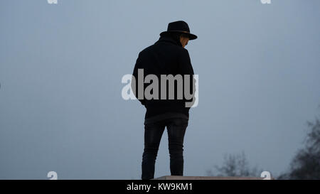 Mann in Trilby Hut gegen bewölkter Himmel Silhouette Stockfoto