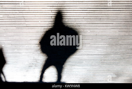Blurry krumme Schatten Silhouette einer Person zu Fuß Straße der Stadt gemusterten Bürgersteig in Schwarz und Weiß Stockfoto