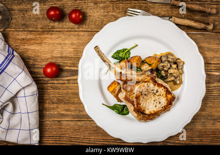 Gebackene Schnitzel oder Kotelett mit Pilzsauce und Kartoffeln mit Spinat Top View Stockfoto