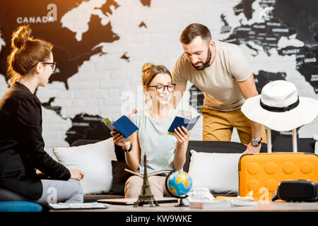 Junge paar schöne sitzend mit Manager im Reisebüro Büro prepairing für einen Sommerurlaub Stockfoto