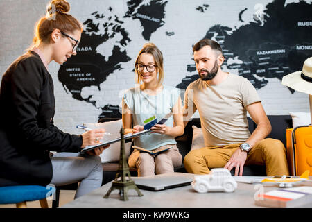 Junge paar schöne sitzend mit Manager im Reisebüro Büro prepairing für einen Sommerurlaub Stockfoto