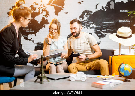 Junge paar schöne sitzend mit Manager im Reisebüro Büro prepairing für einen Sommerurlaub Stockfoto