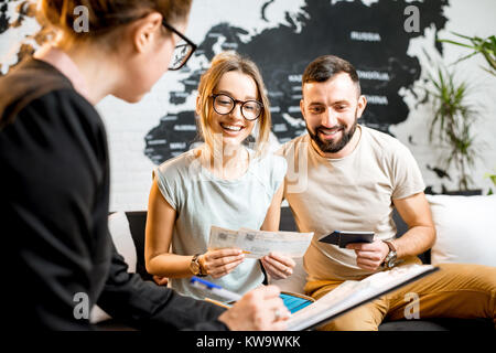 Junge paar schöne sitzend mit Manager im Reisebüro Büro prepairing für einen Sommerurlaub Stockfoto
