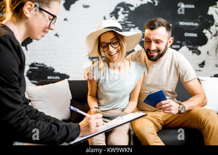 Junge paar schöne sitzend mit Manager im Reisebüro Büro prepairing für einen Sommerurlaub Stockfoto