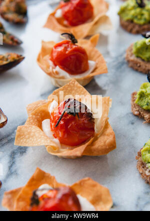 Kirschtomate mit Frischkäse in Blätterteig Häppchen auf grauem Marmor Stockfoto