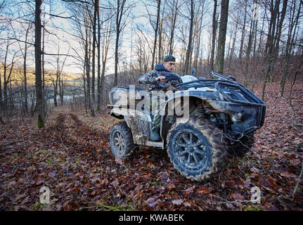 Junge Jäger auf ein Quad auf der Suche nach Spiel im Wald Stockfoto