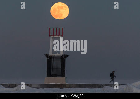 Chicago, USA. 1 Jan, 2018. Ein Mann geht über die Anlegestelle am Eis bedeckt North Avenue Beach als supermoon auf einer der kältesten Tage des neuen Jahres seit Jahrzehnten steigt. Der Mond ist an seinem nächsten Punkt, dem Perigäum, auf der Erde während seiner monatlichen Orbit und erscheint 30 % mehr Helligkeit und 14 % größer. Januar 2018 sieht eine supermoon als "Wolf Moon' am 1. Januar und ein "Blue Moon" am 31. Januar bekannt. Credit: Stephen Chung/Alamy leben Nachrichten Stockfoto